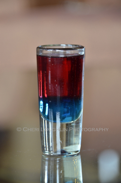 The Patriot Shot for 4th of July. Blue Curacao with float of Bubbly Red Moscato. Garnish with pierced diced apple if desired. - photo and recipe by Mixologist Cheri Loughlin, The Intoxicologist